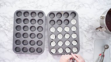 Düz yatıyordu. Adım adım. Mini çikolatalı kek pişirmek için kek kalıplarıyla kek tepsisi hazırlıyorum..