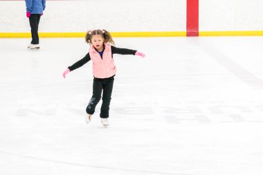 Küçük kız buz pistinde artistik patinaj yapıyor..