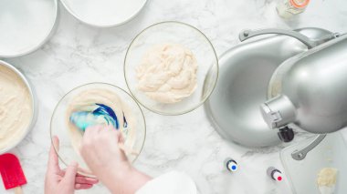 Adım adım. Düz yatıyordu. Üç katlı vanilyalı kek pişirmek için yemek boyasını kek hamuruna karıştırıyorum..