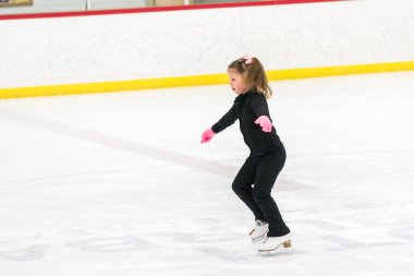 Küçük kız buz pistinde artistik patinaj yapıyor..