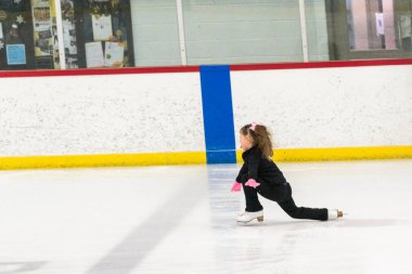 Küçük kız buz pistinde artistik patinaj yapıyor..