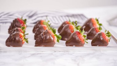 Adım adım. Çikolata kaplı çilek hazırlamak için organik çilekleri erimiş çikolatayla bir kaseye daldırmak..