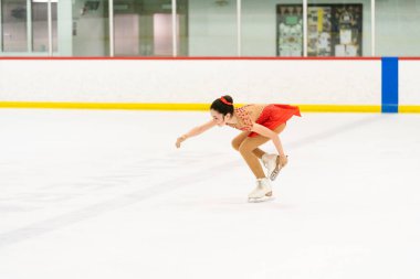 Genç kız buz pateni pistinde artistik patinaj yapıyor..