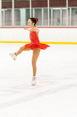 Genç kız buz pateni pistinde artistik patinaj yapıyor..