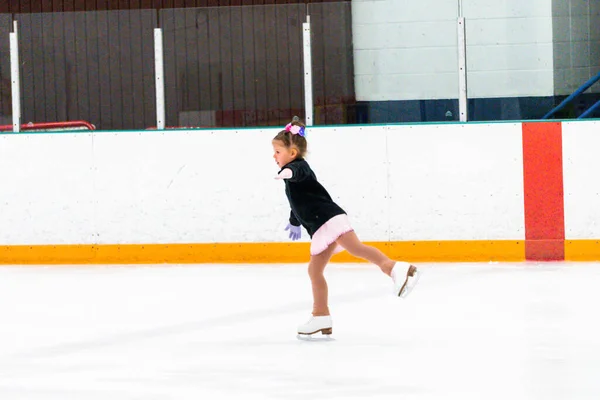 小女孩穿着粉红的莱茵石裙子练习花样滑冰 — 图库照片