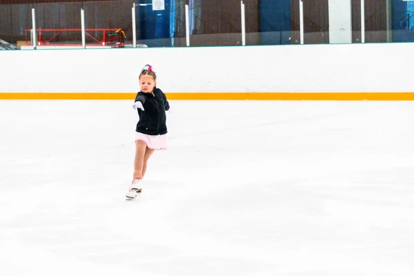 小女孩穿着粉红的莱茵石裙子练习花样滑冰 — 图库照片