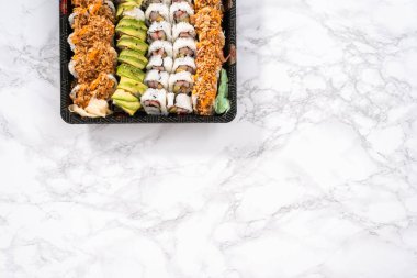 Düz yatıyordu. Önceden paketlenmiş suşi ve suşi çeşitleri plastik tepside..