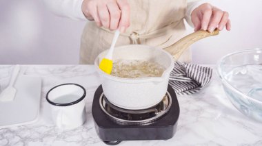 Adım adım. Küçük elektrikli ocağın üzerinde küçük bir tencerede karamelize şeker.