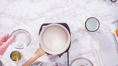 Düz yatıyordu. Adım adım. Küçük elektrikli ocağın üzerinde küçük bir tencerede karamelize şeker.