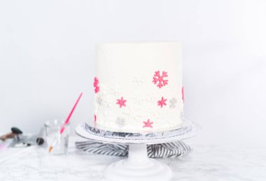 Beyaz İtalyan tereyağlı uzun yuvarlak bir pasta süslemek ve şekerli kar taneleriyle süslemek..