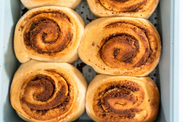 Freshly baked cinnamon rolls in a blue baking pan.