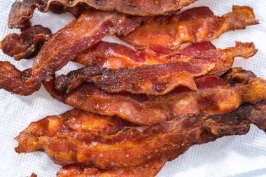 Beyaz tepside pişmiş pastırma şeritleri ve kağıt havlu..