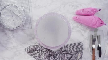 Pembe tereyağlı krema kaplı yuvarlak funfetti kek katmanları.