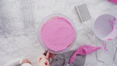 Pembe tereyağlı krema kaplı yuvarlak funfetti kek katmanları.