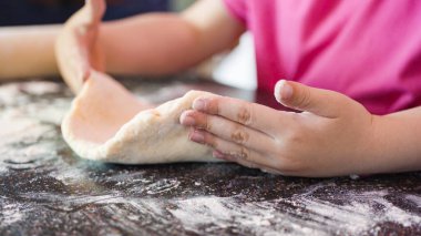 Küçük kız küçük pizzalar için pizza hamuru hazırlıyor..