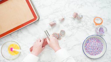 Adım adım. Düz yatıyordu. Hamuru hamur bıçağıyla dilimlemek kırmızı, beyaz ve mavi fırıldak şekerli kurabiyeler pişirmek için.