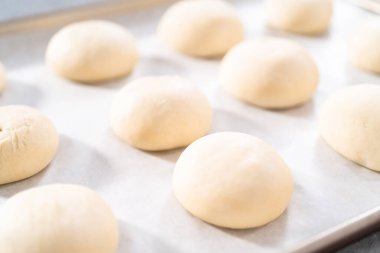 Pişirmeden önce parşömen kağıdıyla kaplanmış fırınlanmış ekmek ruloları..