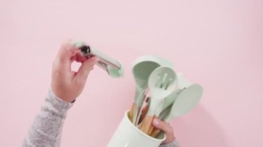Pembe arka planda ahşap saplı yeni mavi silikon mutfak aletleri..