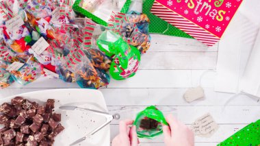 Düz yatıyordu. Adım adım. Ev yapımı macadamia şekerlemesi küçük hediye paketlerine konuyor..