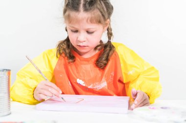 Evde akrilik boyalı bir sanat projesi üzerinde çalışan küçük bir kız..