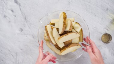 Düz yatıyordu. Adım adım. Fırında patatesleri baharatla pişirmek için patates dilimlerini bir kase suya batırıyorum..