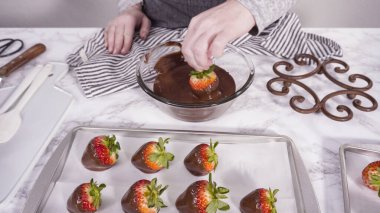 Adım adım. Çikolata kaplı çilek hazırlamak için organik çilekleri erimiş çikolatayla bir kaseye daldırmak..