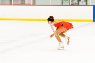 Genç kız buz pateni pistinde artistik patinaj yapıyor..