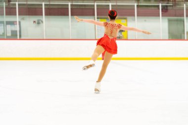 Genç kız buz pateni pistinde artistik patinaj yapıyor..