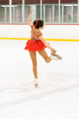 Genç kız buz pateni pistinde artistik patinaj yapıyor..