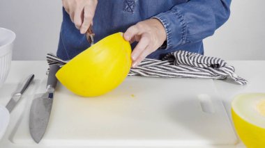 Adım adım. Beyaz bir kesme tahtasının üzerinde altın lezzetli kavun dilimliyorum..