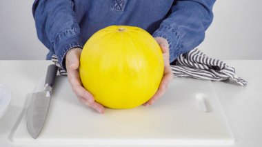 Adım adım. Beyaz bir kesme tahtasının üzerinde altın lezzetli kavun dilimliyorum..