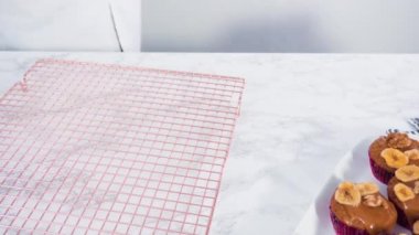 Ceviz ve muz cipsiyle süslenmiş, ev yapımı karamel serpiştirilmiş muzlu fındıklı çörekler pişirir..