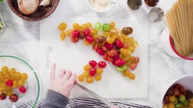 Tek demlik makarna tarifi yapmak için beyaz bir kesim tahtasıyla sebze kesmek..
