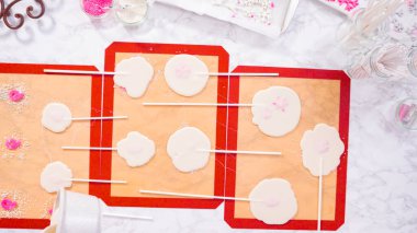 Düz yatıyordu. Ev yapımı lolipoplar yapmak için silikon paspaslara karamelize şeker dökmek..