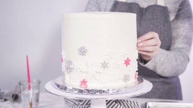 Adım adım. Yuvarlak funfetti pastasını pembe ve beyaz fondant kar taneleriyle süslüyorum..