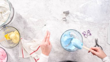 Düz yatıyordu. Adım adım. Tek boynuzlu at meringue kurabiyesi pişirmek için metal uçlu boru torbalarına krema karıştırılıyor..