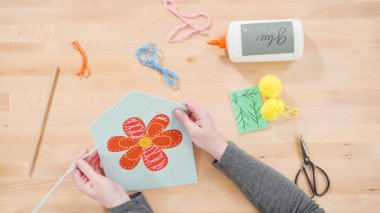 Anne çocuklara el sanatları masasında dikiş setiyle dikiş dikmeyi öğretiyor..