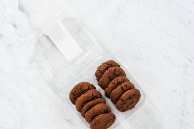 Düz yatıyordu. Plastik bir kapta taze pişmiş çifte çikolatalı kurabiye..