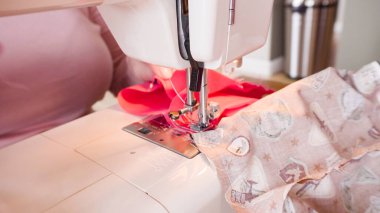 Koronavirüs salgını için dikiş makinesiyle pamuk yüz maskesi dikiyorum..