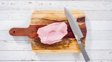 Düz yatıyordu. Ağaç kesme tahtasıyla organik ballı jambon kesmek.