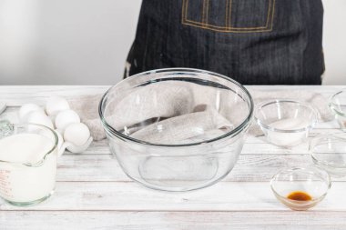 Ahşap bir masada yumurtalı ekmek hazırlamak için cam karıştırma kabındaki malzemeler..