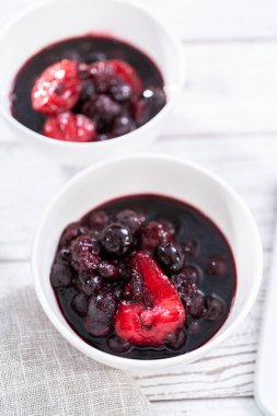 Ev yapımı böğürtlen kompostosu ahşap bir masada küçük beyaz kaselerde..