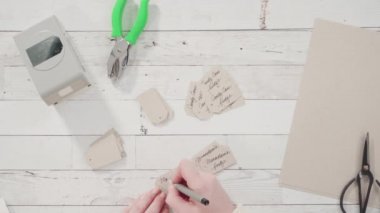 Düz yatıyordu. Adım adım. Kahverengi kağıttan hediye etiketlerini kağıt punçla kesiyor..