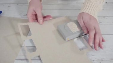 Zaman aşımı. Adım adım. Kahverengi kağıttan hediye etiketlerini kağıt punçla kesiyor..