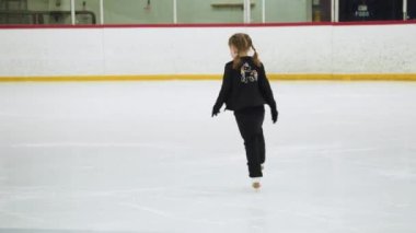 Küçük kız buz pateni pistinde artistik patinaj yapıyor..