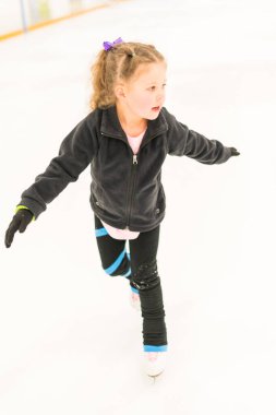 Küçük artistik patinajcı kapalı bir buz arenasında pratik yapıyor..