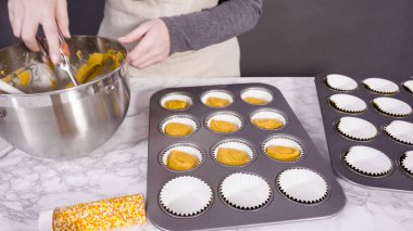 Balkabağı aromalı kek hamuru. Hamur hamuru kepçesiyle kapkek tepsisine dolgu malzemesi..