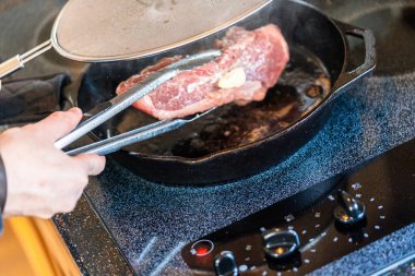 Elektrikli fırının üstünde kızgın demir tavayla New York bifteği kızartıyorum..