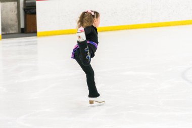 Küçük kız buz pistinde artistik patinaj yapıyor..