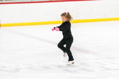 Küçük kız buz pistinde artistik patinaj yapıyor..